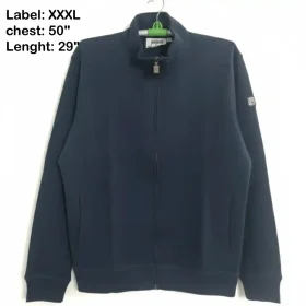 A navy blue full-zip jacket with a high stand collar, ribbed cuffs, and a small square patch logo on the upper left sleeve, photographed on a hanger.