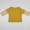 Back view of a plain mustard yellow long-sleeve toddler T-shirt with a white collar and snap buttons at the neck.