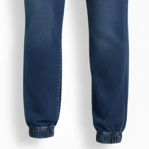 Image of dark indigo blue denim joggers, folded, showing the elastic waistband, back pocket, and DENIM JOGGER tag.